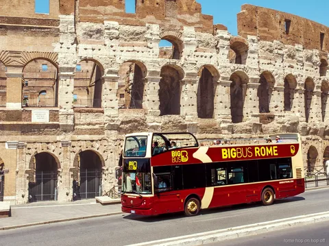 Bus touristique de Rome Hop-On Hop-Off à impériale ouvert passant devant le Colisée