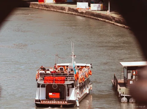 Crucero hop-on hop-off del río Tíber en Roma pasando bajo un puente histórico