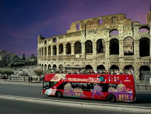 Bus hop on hop off Roma notturno davanti al Colosseo illuminato